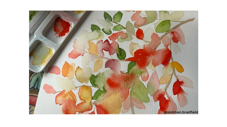 A watercolor painting of abstract leaves in red, green, and yellow tones sits beside a paint palette with mixed colors.